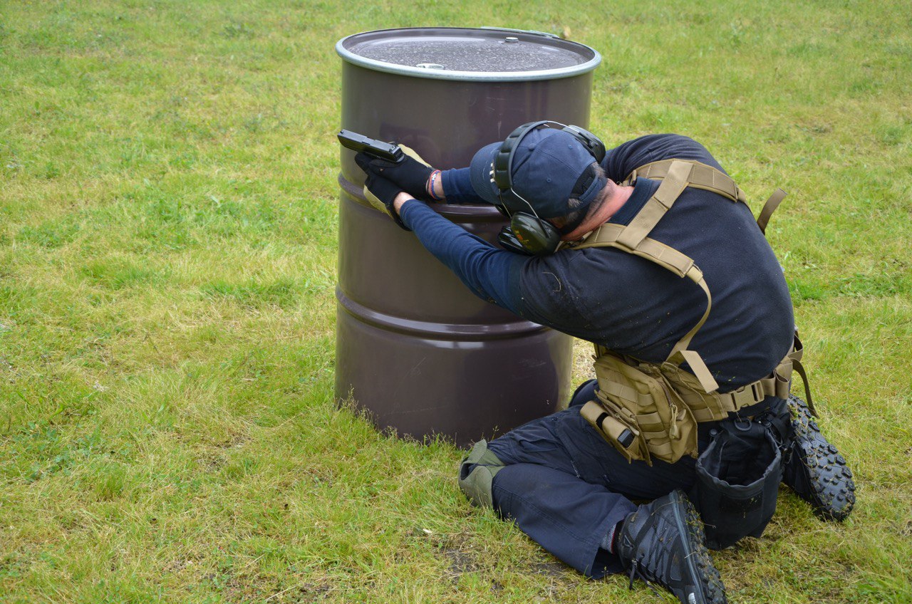 Muškarac puca iz pištolja iza bureta